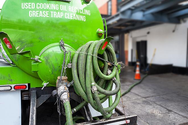 a professional plumber using a pump to empty a grease trap in Kaneville